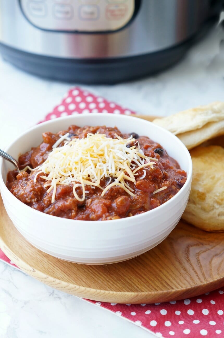 Image of beef chili in a bowl in front of an instant pot