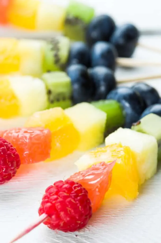 image of brightly colored fruit kabobs with blueberries, kiwie, pineapple, mango, raspberries,a nd grapefurit