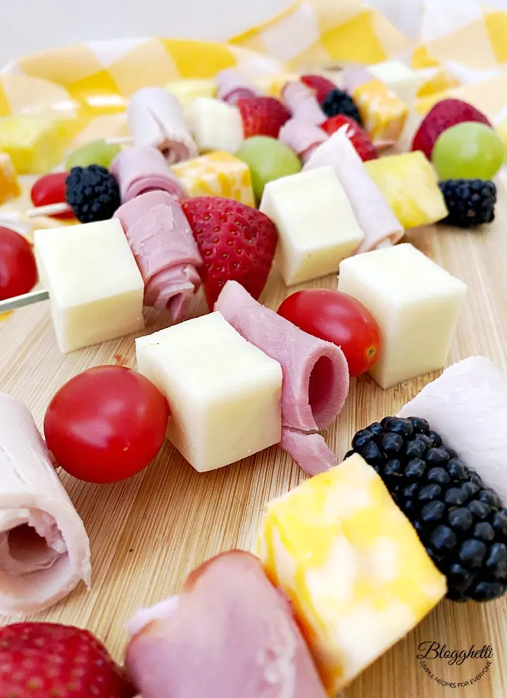 image of meat and cheese skewers with tomatoes and fruit