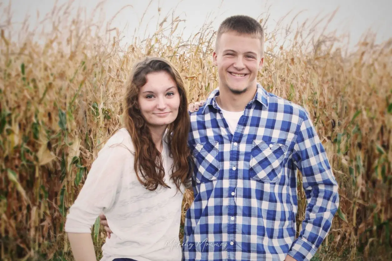 image of a young man and woman standing in front of a corn field