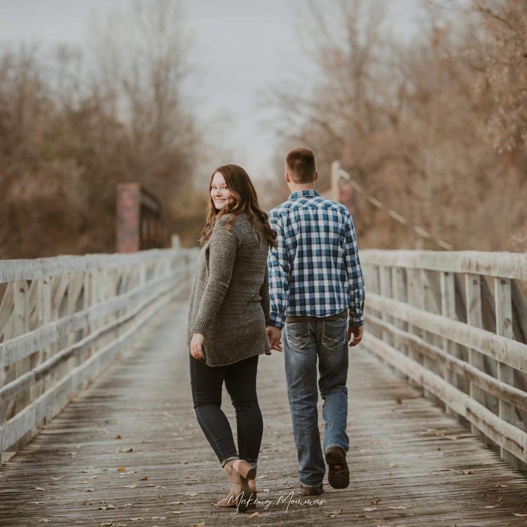 image of a young man and woman walking on a bridge in the fall