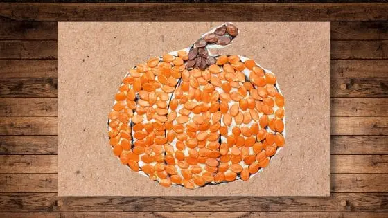 image of a pumpkin covered in orange and brown pumpkin seeds on a brown paper