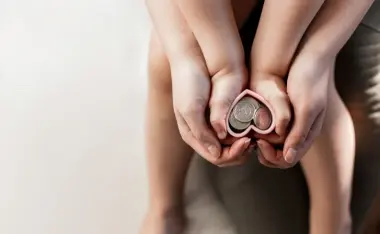 image of a mom and child hands holding a heart with money in it