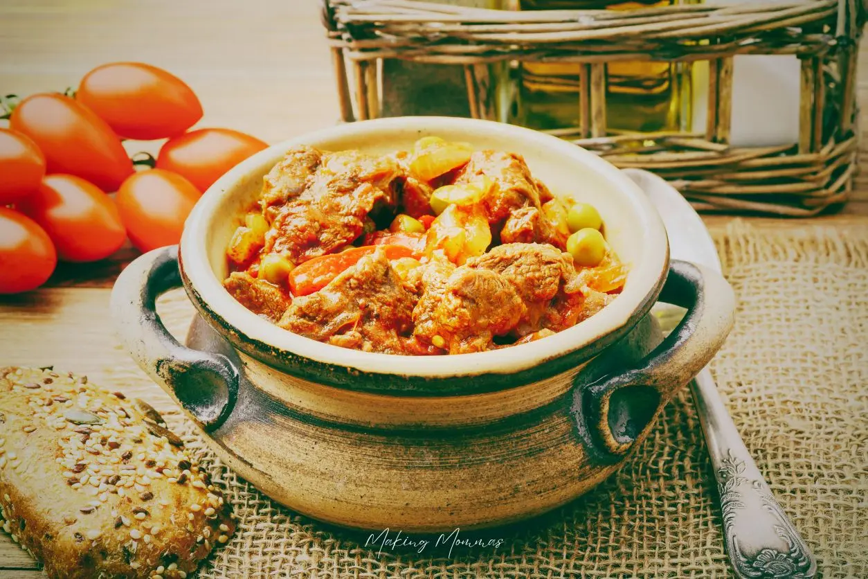 image of a vintage pot of stew sitting next to a basket and tomatoes