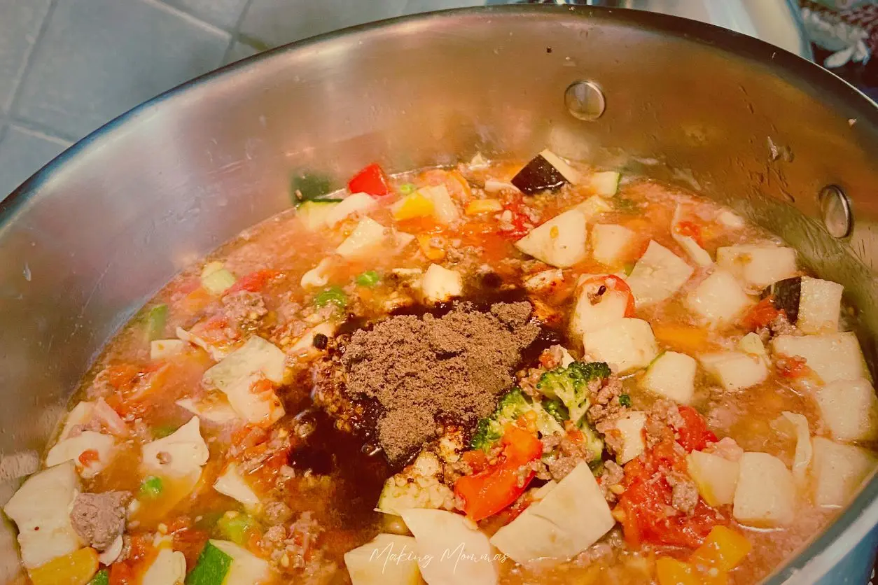 Image of hamburger, broccoli, carrots, red peppers, yellow peppers, onions, peas, and potatoes, with a beef broth powder, in a soup base.