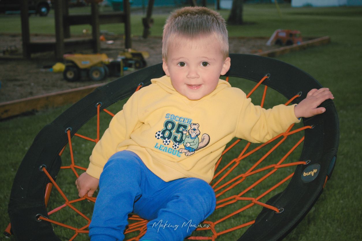 image of a little boy sitting on a bouncy chair in front of a sandbox at night