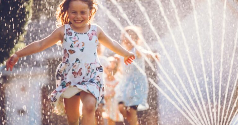 image of girl running through sprinkler
