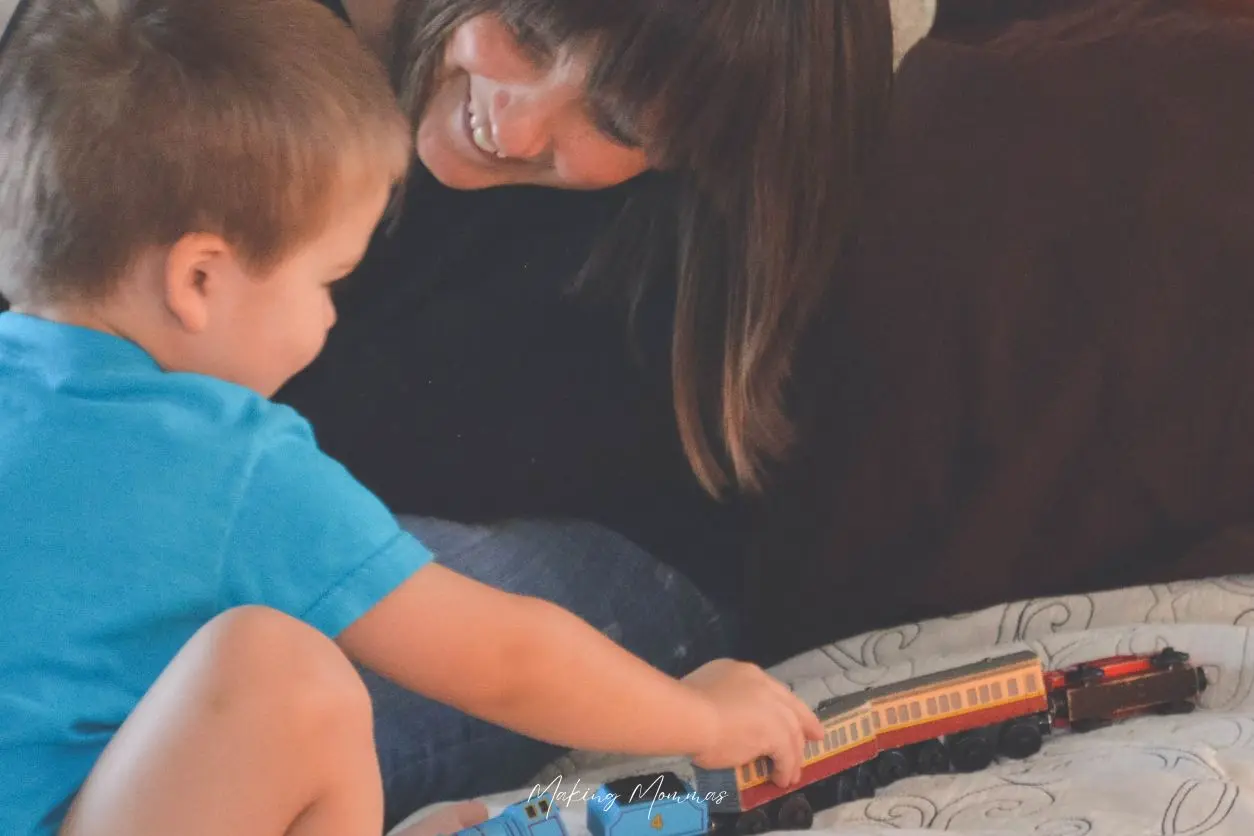 image of a mom and son playing trains on a bed