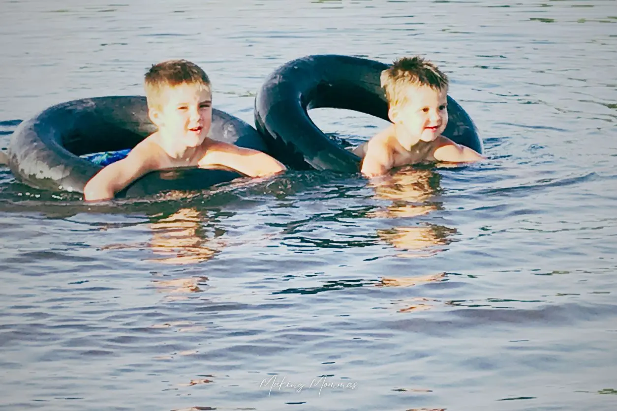 image of boys in a tire tube floating in the water