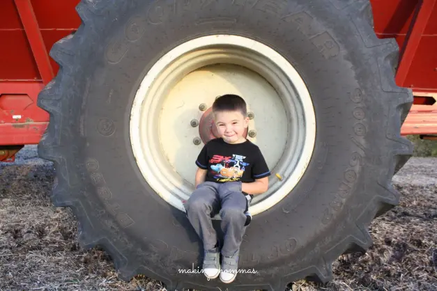 a boy sitting on a tractor tire
