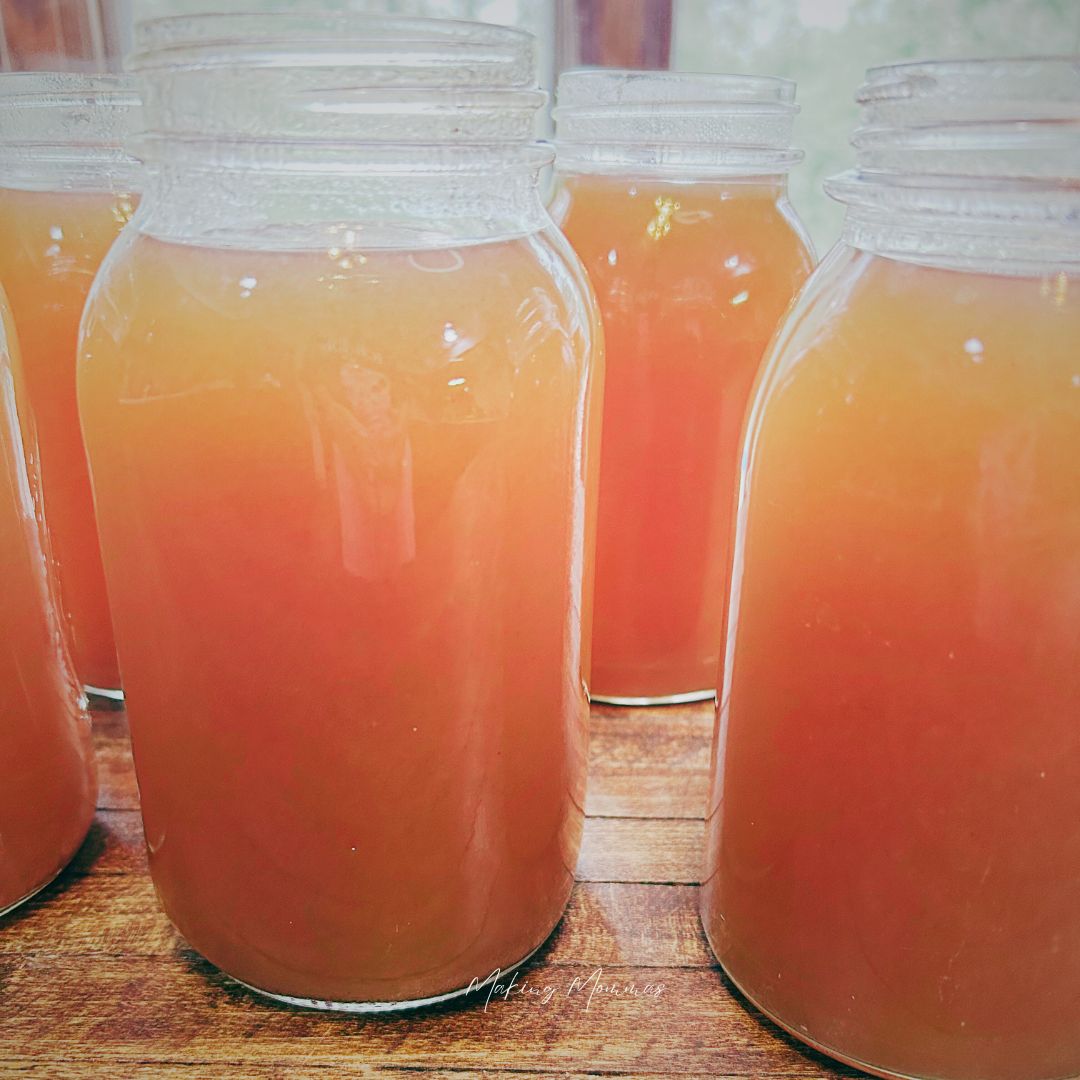 Jars of homemade apple cider arranged on a wooden table, glowing with a warm amber color, capturing the essence of fresh, fall-inspired flavors.