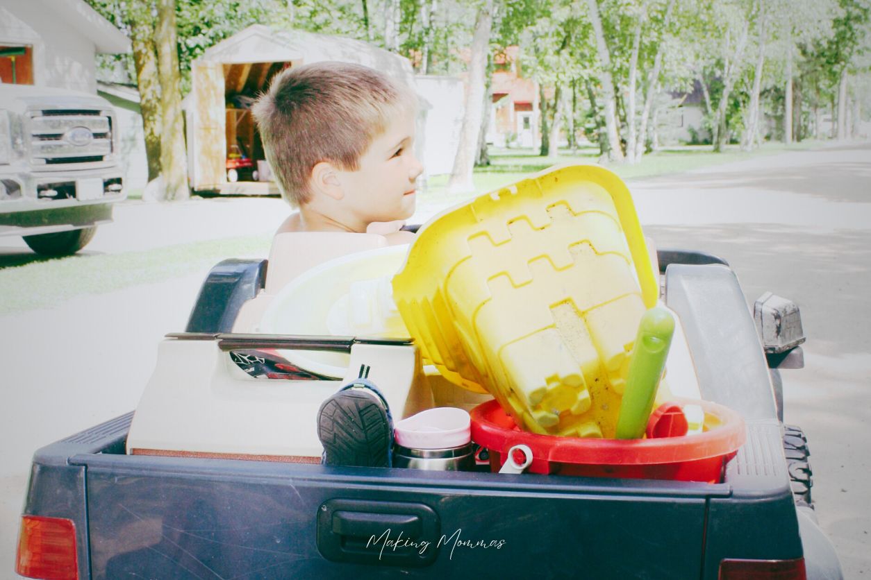 image of a little boy hauling his sand toys in the back of his toy pickup