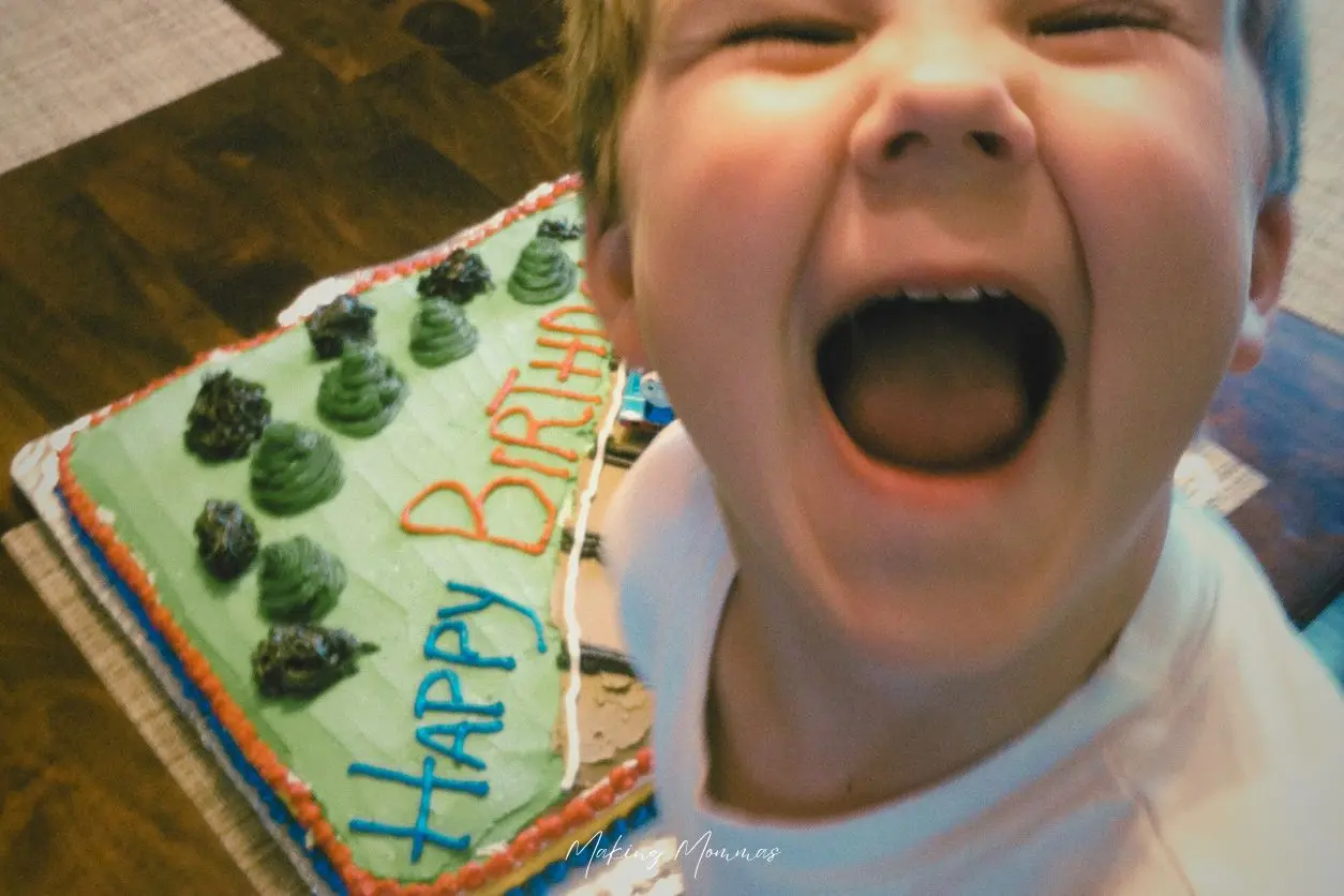 image of a little boy smiling goofy by a birthday cake