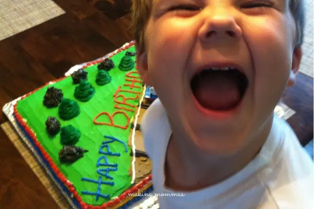 image of a smiling boy in front of a birthday cake