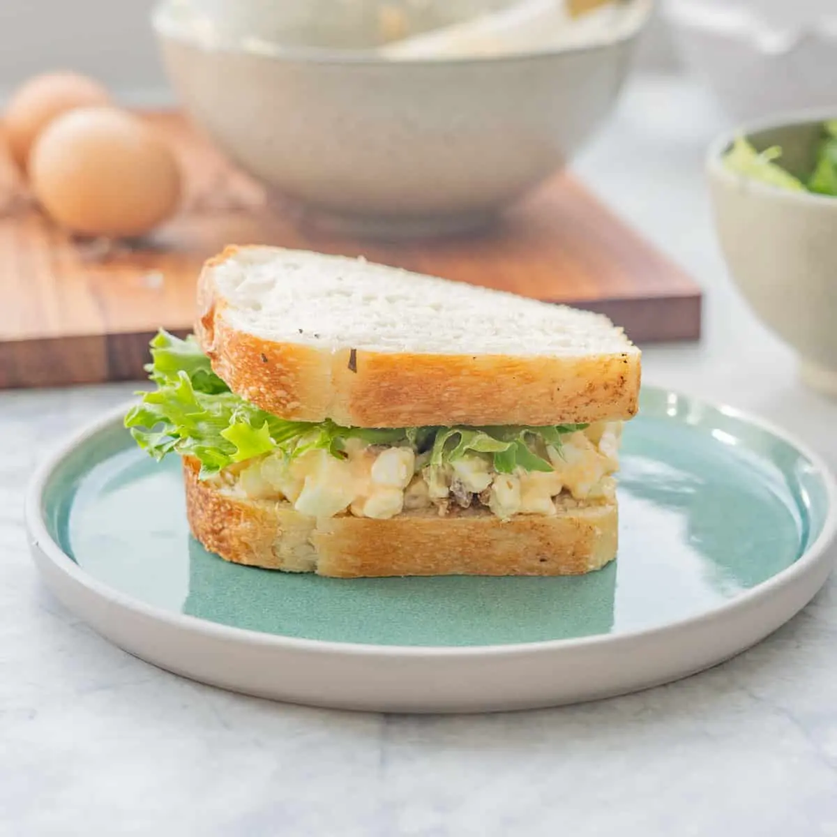 image of an egg salad sandwich on a blue plate