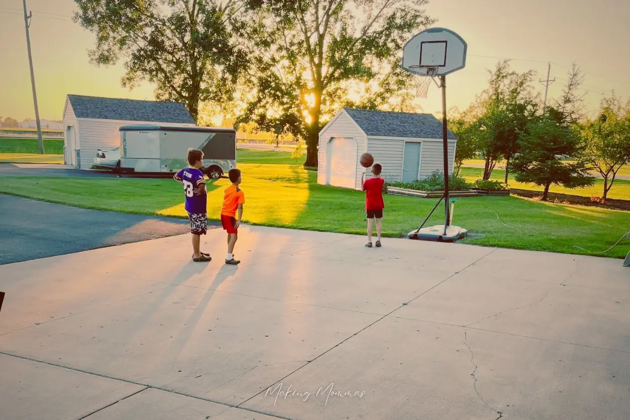 image of three boys playing basketball outside in the evening
