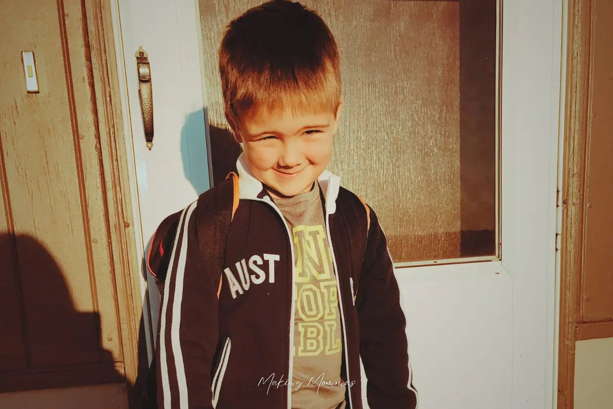 image of a little boy in front of a door with a school backpack on