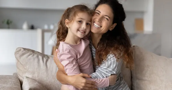 image of a mom and girl smiling and snuggling
