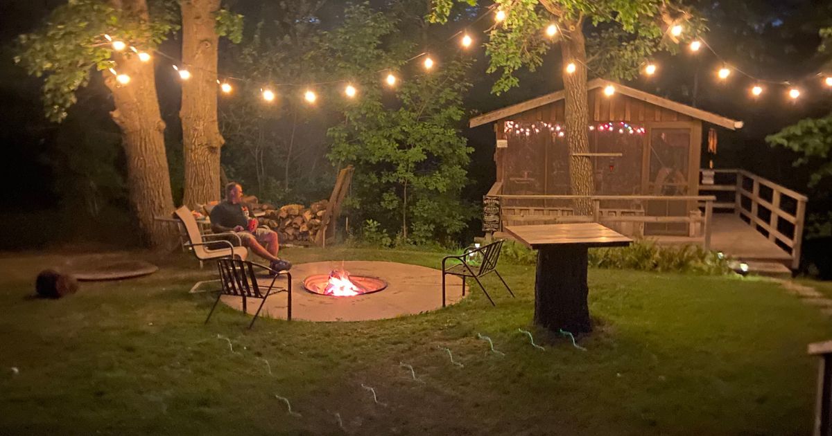 image of man at a fire in front of a treehouse