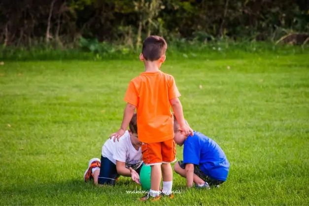 three boys getting a football ready to kick