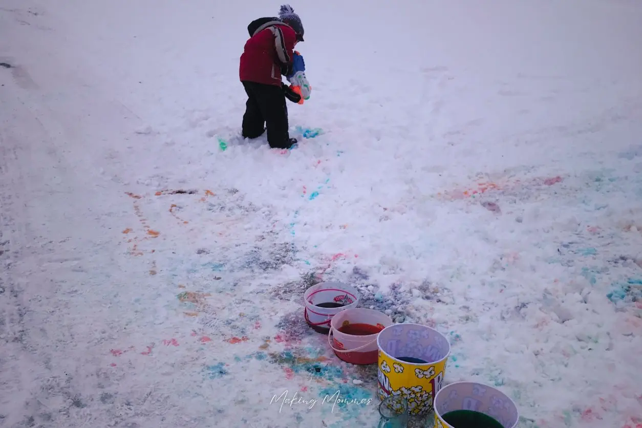 image of a kid painting the snow with a water gun and colored water