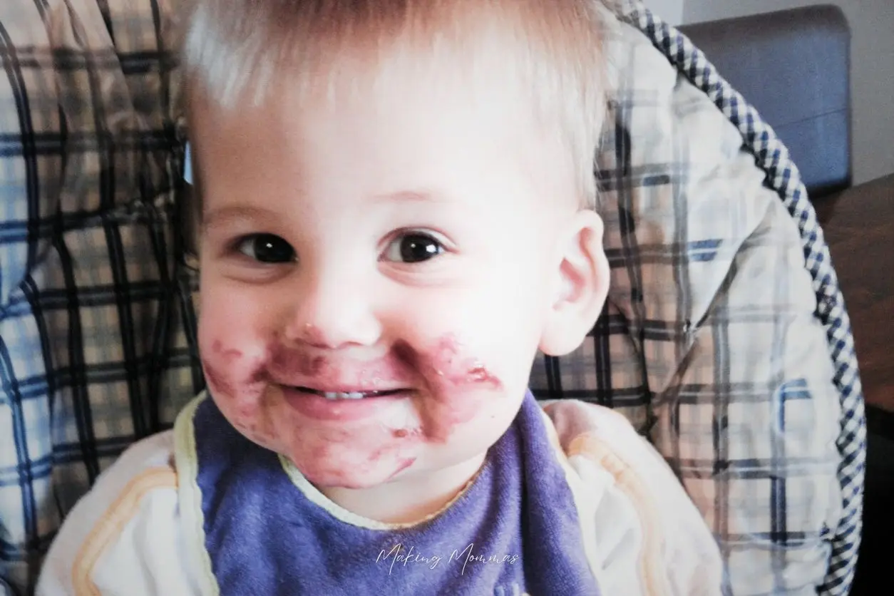 image of a little boy in a high chair with jelly smeared on his face