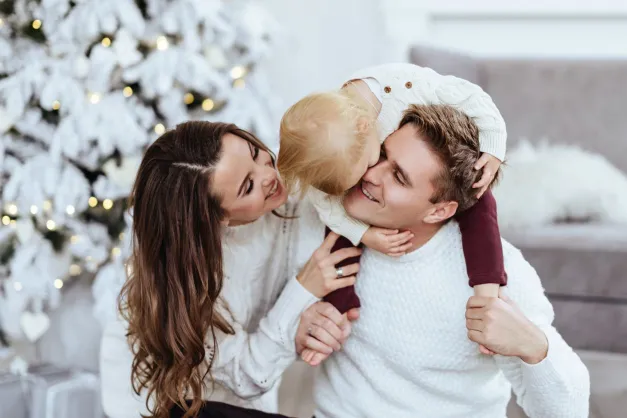 image of mom, dad, and baby in front of a Christmas tree