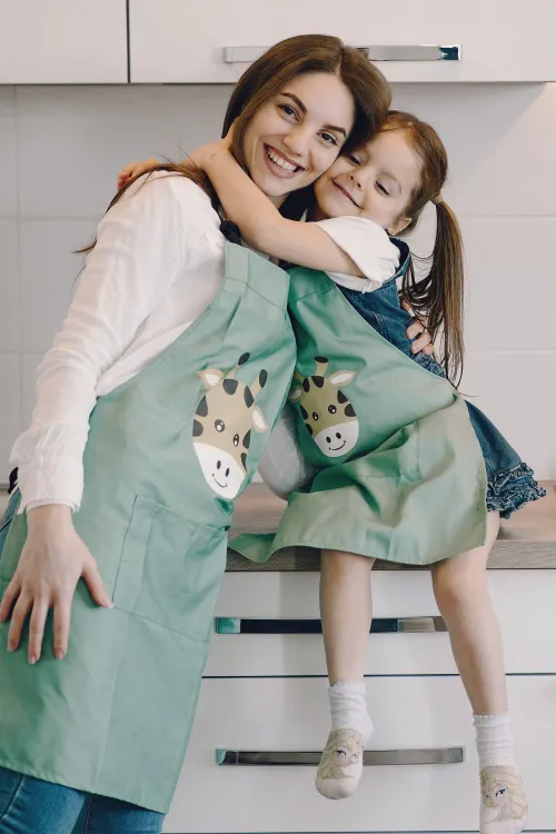 mother and daughter wearing matching aprons hug in the kitchen