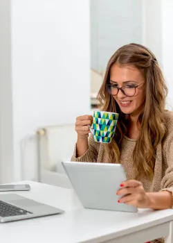 woman sipping coffee looking at tablet