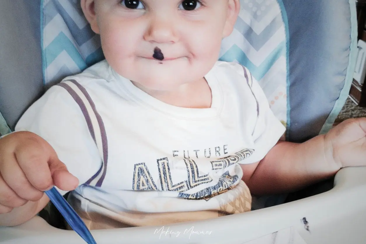 image of a toddler painting in a high chair