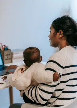 mom at desk and computer holding baby