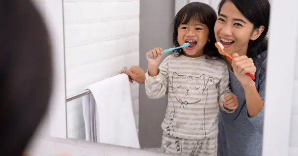 image of a mom and little girl brushing their teeth