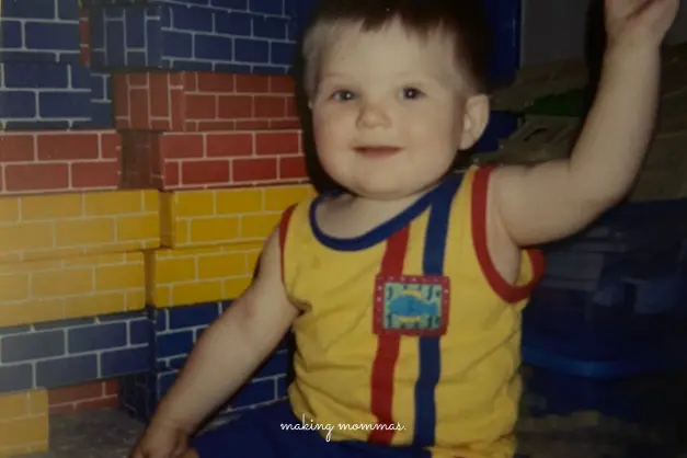image of a boy in bright tank top playing by red yellow and blue blocks.