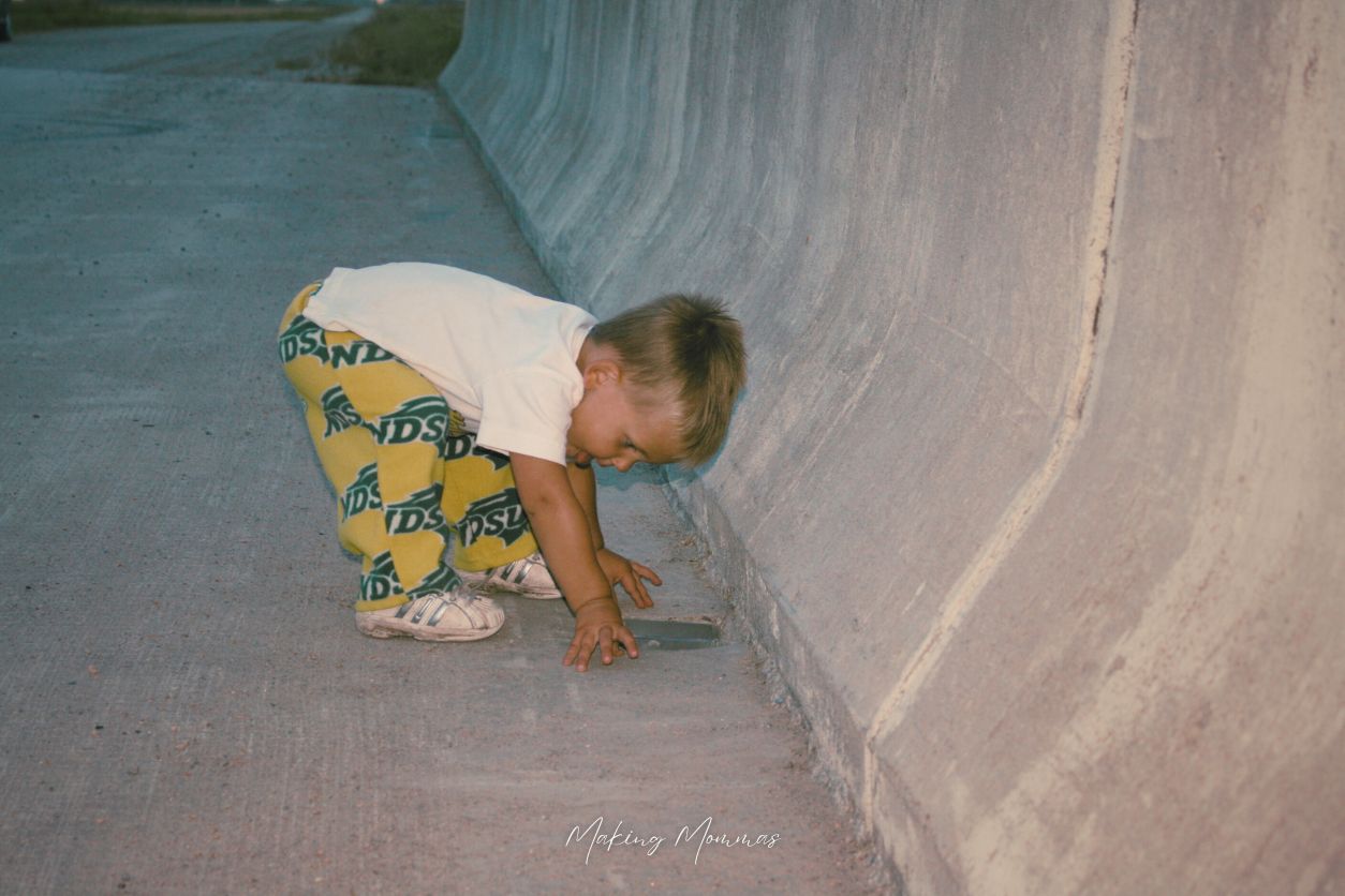 image of a little boy looking through a hole in the cement bridge