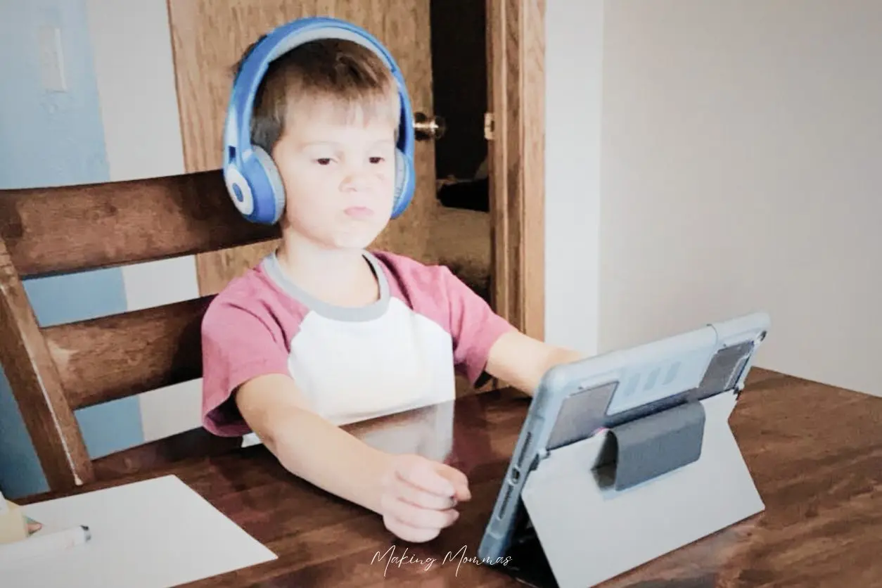 image of a little boy with headphones on watching a device at a table