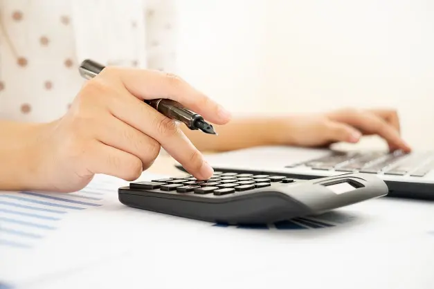 image of a woman using two calculators and holding a pen