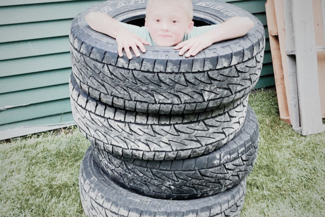 image of a little boy popping out of a tower of tires.