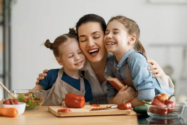 image of mom laughing with her daughters in the kitchen