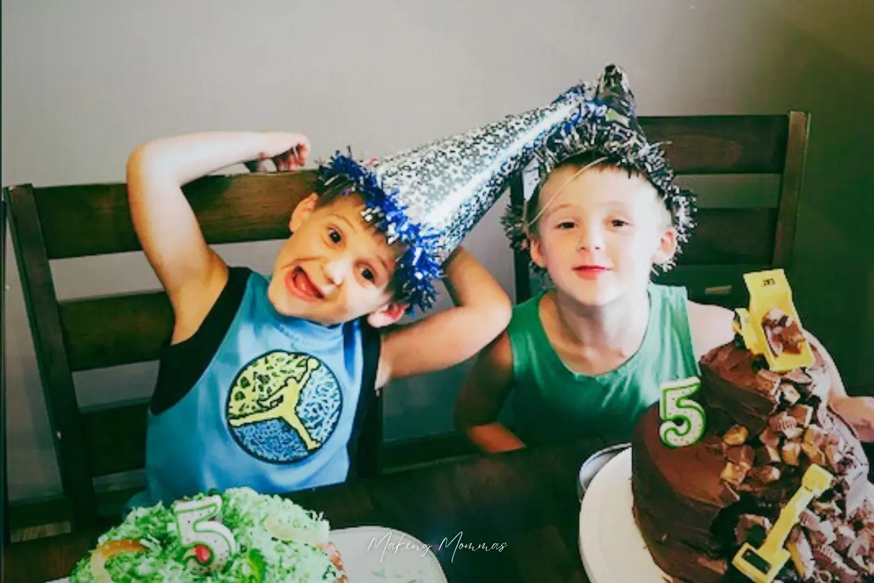 image of two boys in birthday hats sitting with birthday cakes