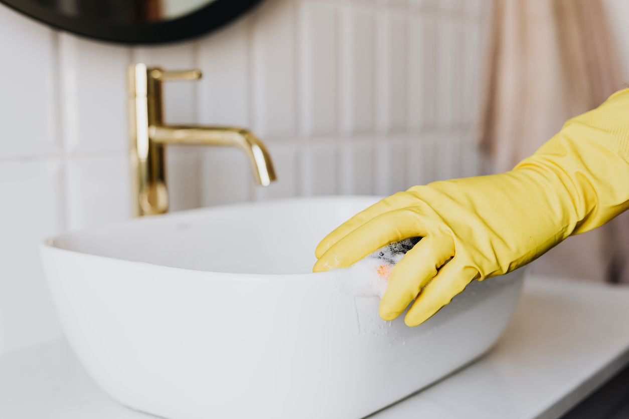 image of a woman wearing yellow gloves cleaning her sink