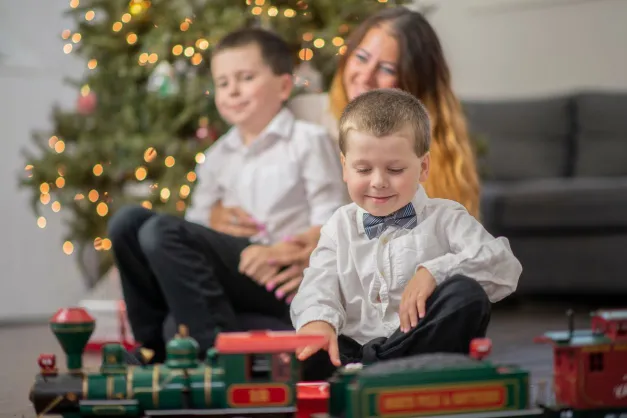 image of two boys playing with a train on Christmas with mom