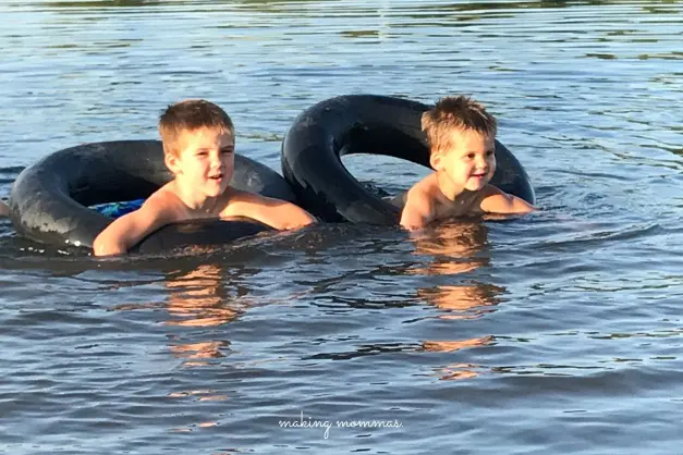 two boys playing in inner tubes in the lake