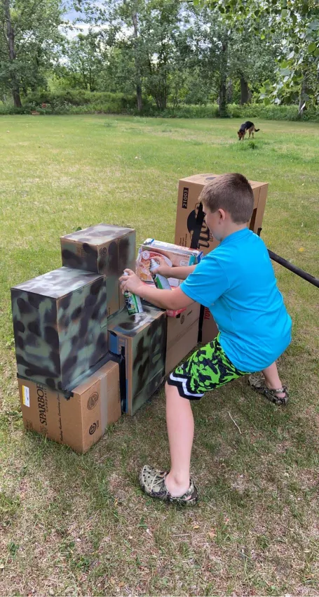 image of boy spray painting cardboard boxes