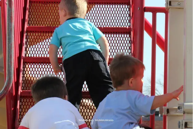 image of three small boys going up a playground ladder