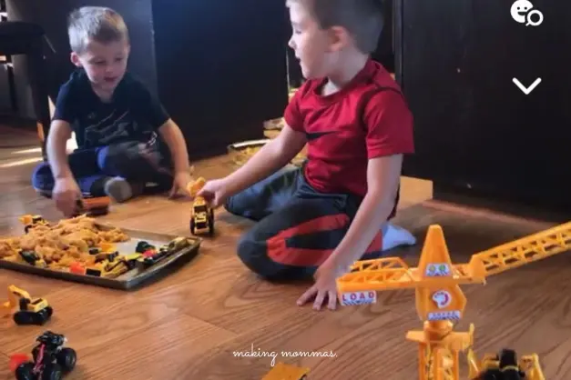 image of two boys playing with construction toys on the floor in moon sand