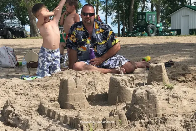 a boy doing the dab after making a sand castle