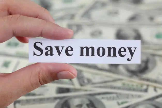 image of someone holding the words "save money" in front of a pile of money