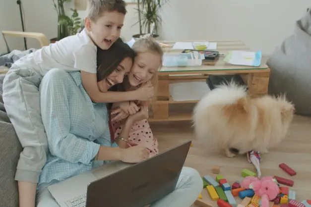 image of a mom working on a computer while kids climb on her