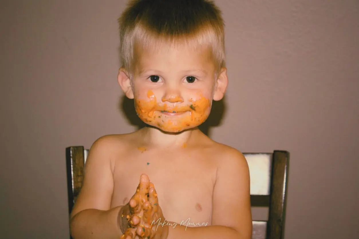 image of a boy sitting on a chair with orange all over his face and hands