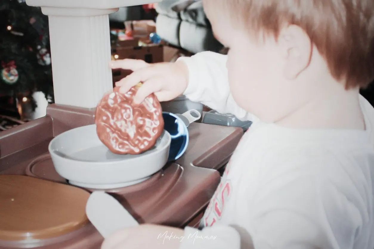 image of a little boy cooking a burger in his toy kitchen